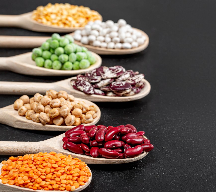 Why are legumes banned by the Paleo Diet? The image shows six types of legumes in wooden spoons, against a black background.