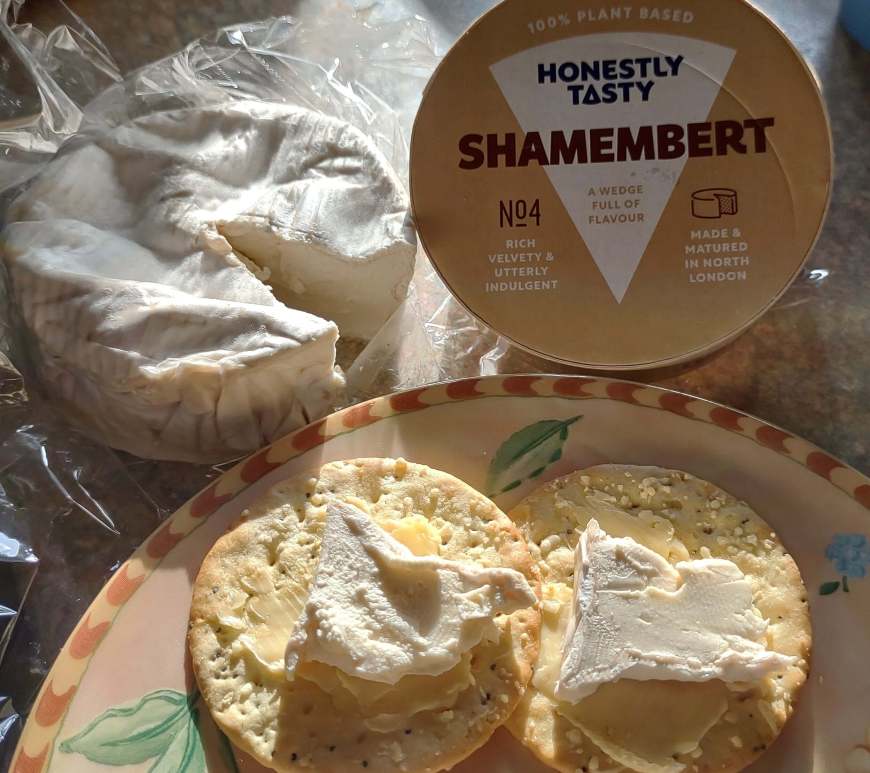 Shamembert - vegan Camembert from Honestly Tasty. The image shows a wedge of plant-based Camembert cheese on a plate, next to a cracker spread with some of the cheese. Honestly Tasty raises the bar on vegan cheese.